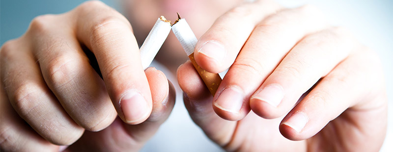 Ein Bild auf dem eine Hand eine Zigarette in zwei Teilt