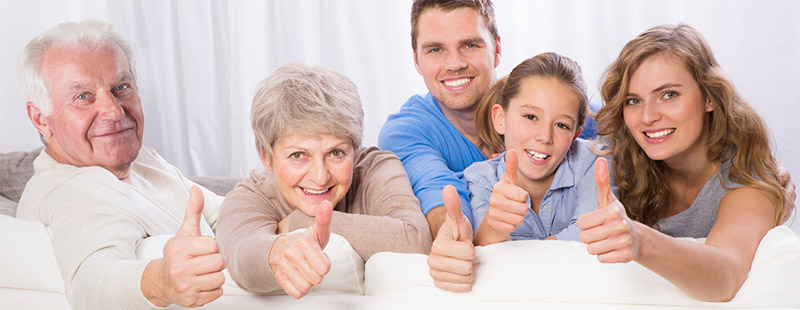 Eine Familie die auf dem Sofa sitzt und die Daumen nach oben streckt