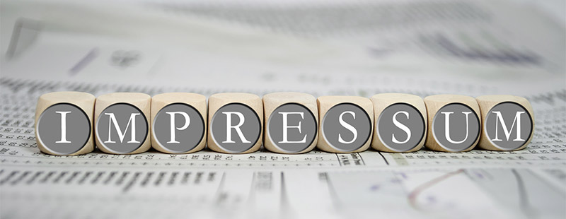 9 Würfel die auf einer Zeitung liegen mit den Buschtaben I-M-P-R-E-S-S-U-M