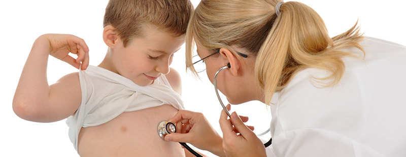 Ein Junge der sein T-Shirt nach oben zieht und eine Ärztin mit dem Stethoskop seine Brust abhört