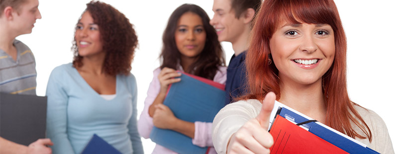 Ein Bild mit 4 Personen im Hintergrund und einer Frau im Vordergrund die den Daumen nach oben zeigt