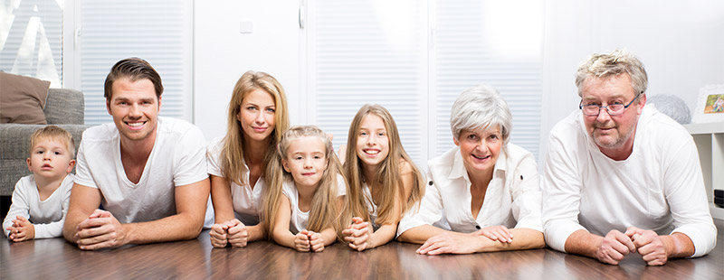 Eine Familie die auf dem Holzboden liegt, alle haben weiße Kleidung an.